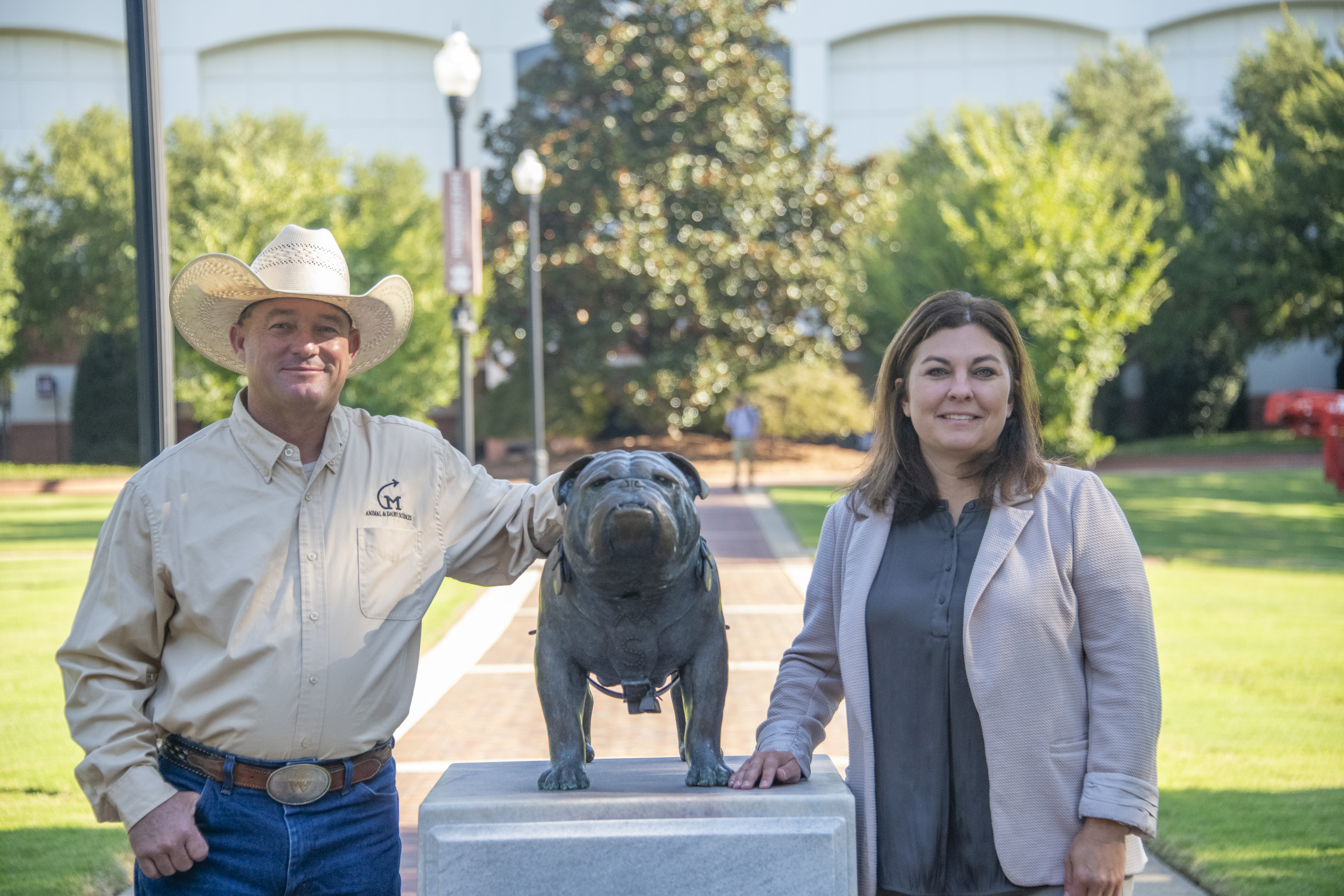 Photo of staff and faculty member by the bully statue